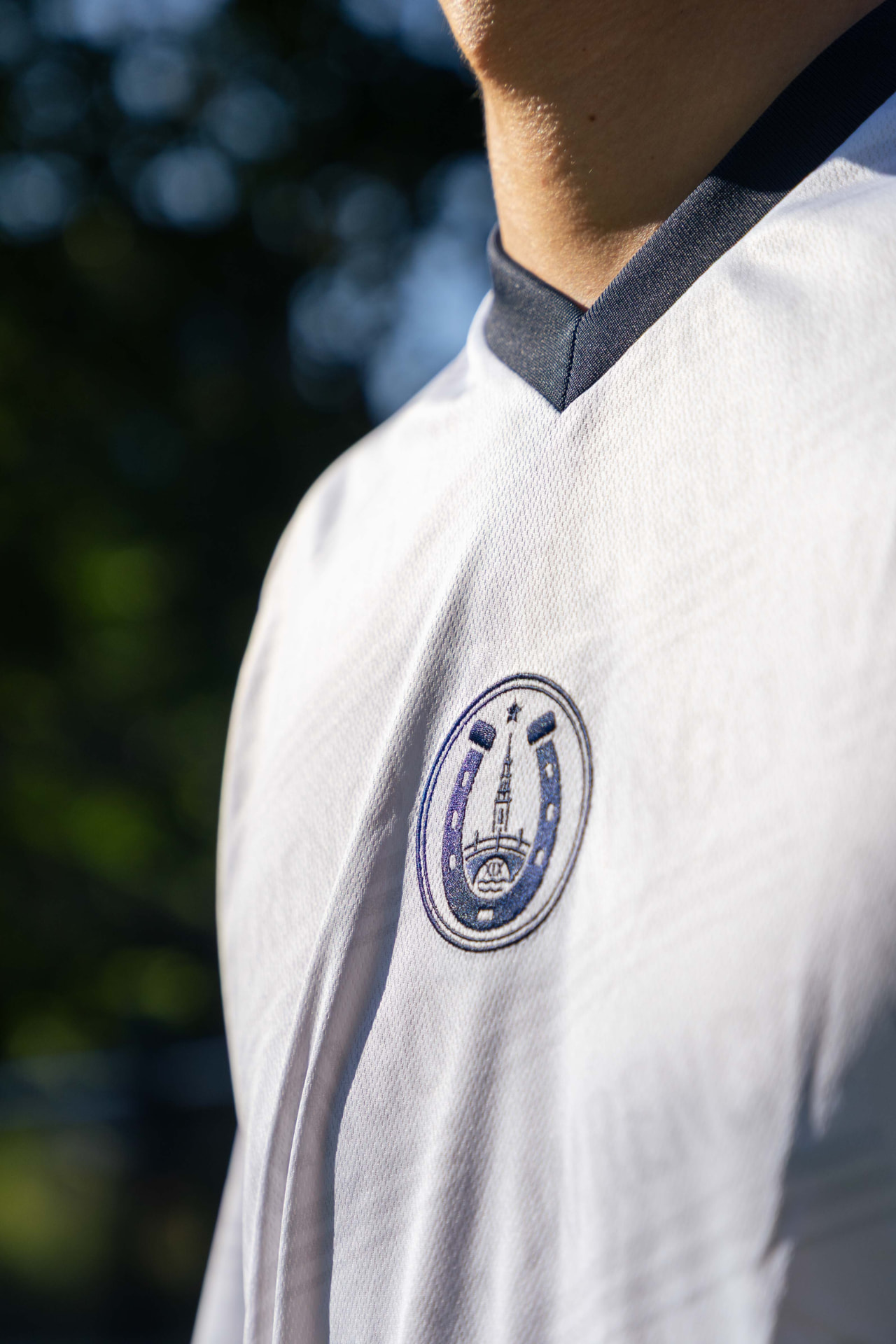 Detail van het geborduurde embleem op het witte shirt